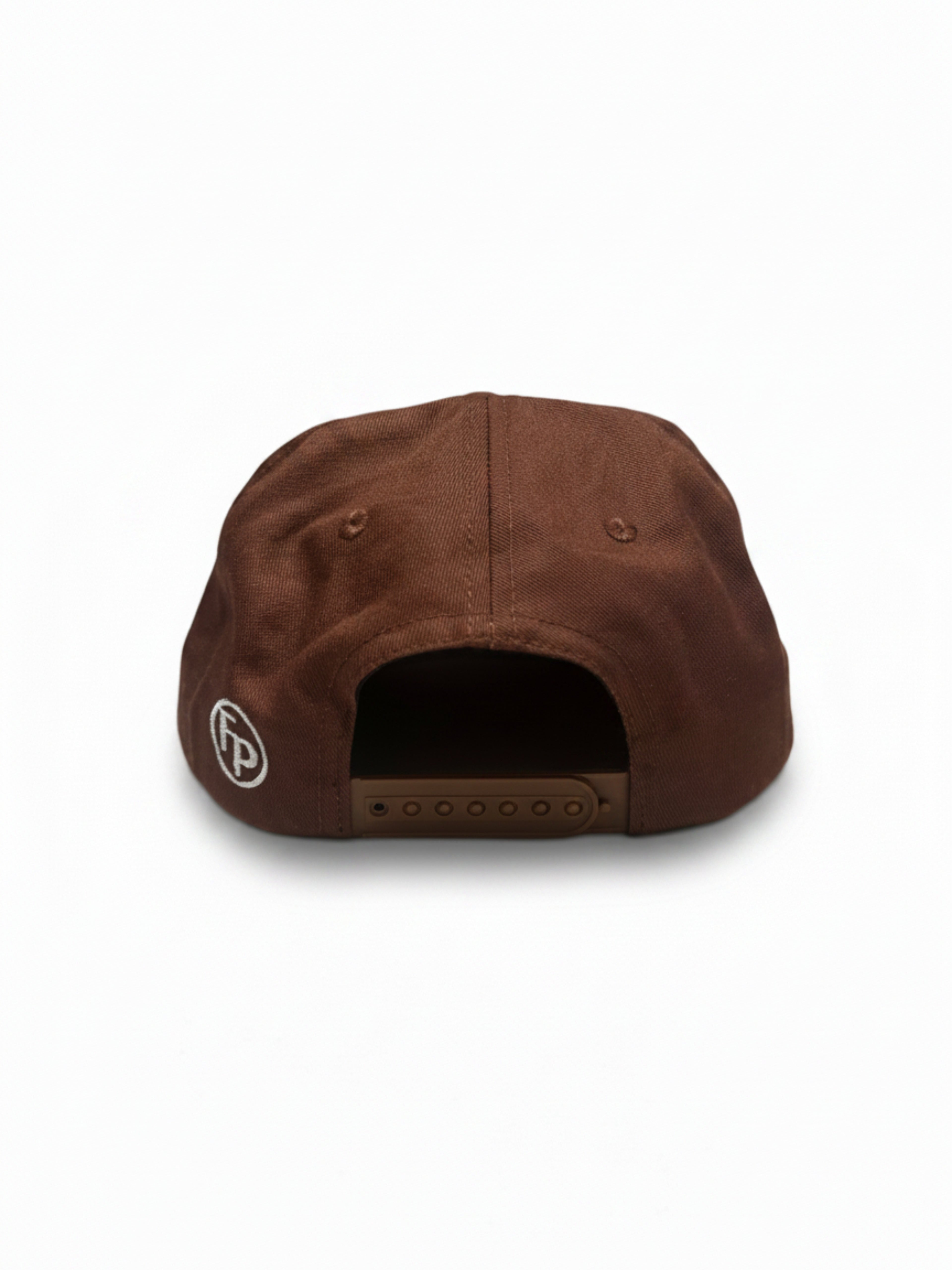A brown snapback cap shown from the back, featuring a small circular white logo with 'FP' on the side and a brown adjustable strap closure.